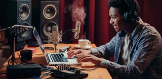 a man in headphones and headphones is sitting at a desk with a laptop