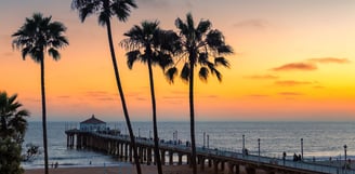 Pier de Santa Monica ao entardecer, com palmeiras ao fundo e o céu colorido pelo pôr do sol na Califórnia