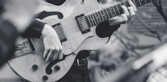 a black and white photo of a man playing guitar 