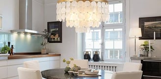 a dining room with a table and chairs under a Capiz shell chandelier