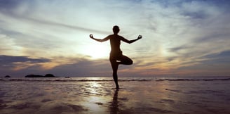 a woman doing yoga exercises on the beach
