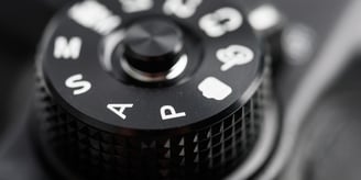 Close-up of a DSLR camera mode dial showing Auto (A), Program (P), settings, symbolising the choice between auto and manual
