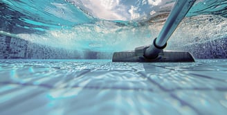 Technician skimming a residential pool with a long cleaning pole under bright sunlight.