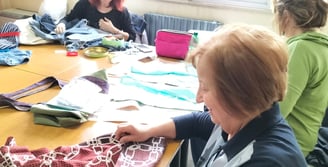a woman is sitting at a table with a bunch of clothes