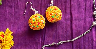 yellow laddoo-shaped polymer clay earrings displayed on a bright purple background