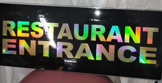 a restaurant entrance sign with a rainbow - colored sign