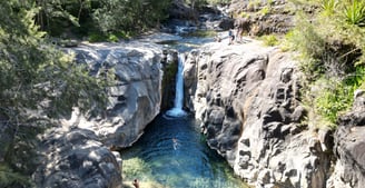 a waterfall in a canyon with a person standing on the side of it