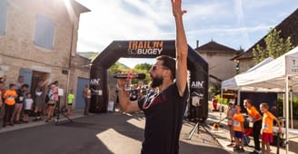 a man in a black shirt speaking with a microphone in a sport event, in front of the starting line