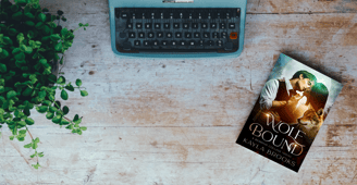 flatlay of Wolf Bound by Kayla Brooks sitting next to a typewriter and plant