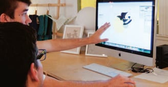 a man sitting at a desk with a computer monitor and a keyboard