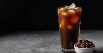 a glass of iced coffee with coffee beans