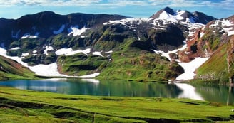 a mountain scene with Ansoo lake and mountains in the background