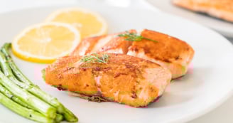 Filetes de salmón a la parrilla acompañados de espárragos y rodajas de limón: una fuente rica en ome