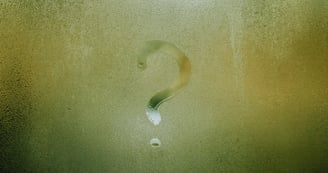 A question mark drawn in condensation on wet glass