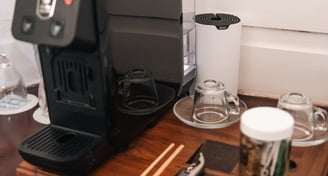 a coffee maker on a table with a cup of coffee