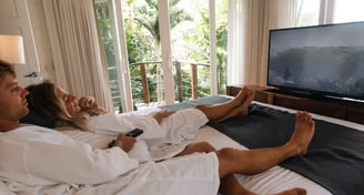 a man and woman sitting on a bed in a hotel room