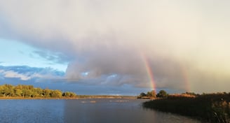 ett vackert svenskt landskap med två regnbågar. en sjö för gäddfiske med fiskeflykt sverige.