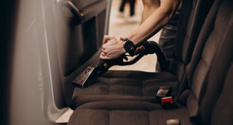 Nettoyage de la banquette arrière d'une voiture avec un aspirateur.