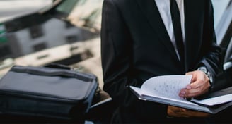 Expert assis sur le capot de sa voiture, travaillant pour aider ses clients à vendre leur véhicule.