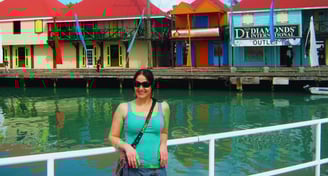 Autora no porto de Antigua. Casinhas coloridas ao fundo.