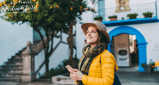 a woman in a yellow jacket and hat with a cell phone