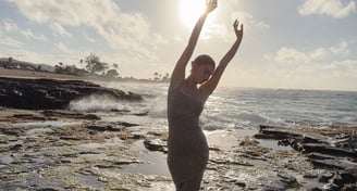 Trina, holistic healer, doing a stretch by the ocean