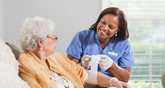 A healthcare worker helping an elderly patient with a wound dressing
