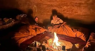 a man and woman sitting in a cave like setting