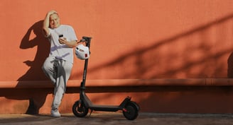 a man leaning against a wall with a scooter
