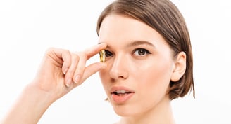 Mujer con una cápsula de omega 3 justo a sus ojos