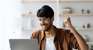 a man wearing glasses being happy looking at his laptop screen representing win in his online business, on blur backdrop.