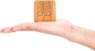 a person holding a small wooden block with a small square shaped object