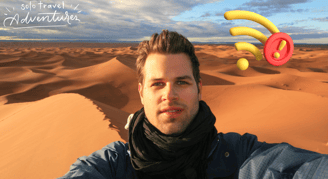 a man with a hat and scarf on a desert