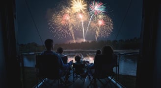 a family watching fireworks in the night sky on an RV deck