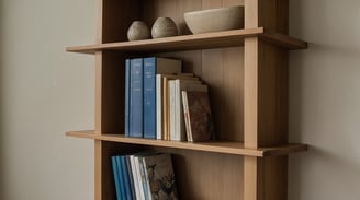 a shelf with books and vases on it