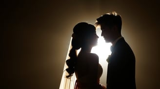 Asian bride and groom standing in front of a bright light