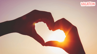 a person making a heart shaped with her hands in the sunset