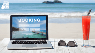 a laptop with an open booking page and a drink