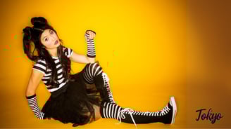 a Japanese woman in striped tights in front of orange background