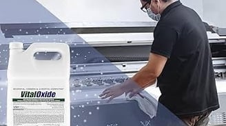 A man in a black shirt is sanitizing a machine.