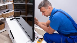 a man in a blue shirt is looking at a television