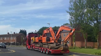 digger on the back of a lorry in a street in stourbridge