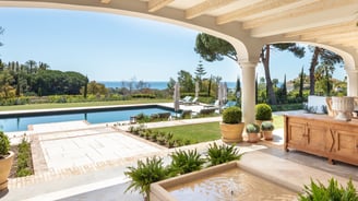 View from the shaded porch across the pool, with the Mediterranean Sea visible in the background.