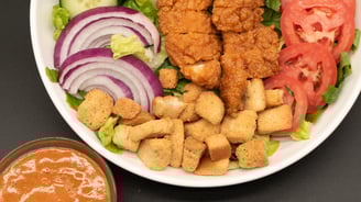 salad in a bowl with a side of dressing