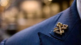 a man in a suit and tie with a gold anchor on it