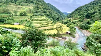a river running through a valley with a small house in the background