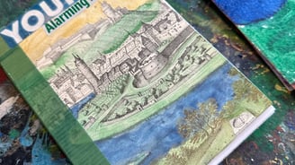 a handmade book with a hand-colored castle and moat on the cover