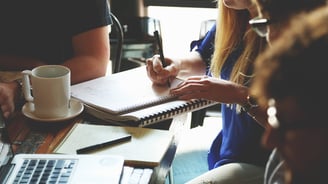 a woman sitting at a table with a notebook and a notebook