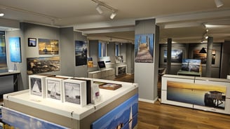 Fotogalerie – Innenraum mit ausgestellten Fotografien an den Wänden und auf Tischen