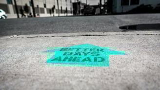 cyan arrow on concrete saying better days ahead